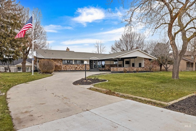 ranch-style home featuring stone siding, curved driveway, a chimney, and a front yard