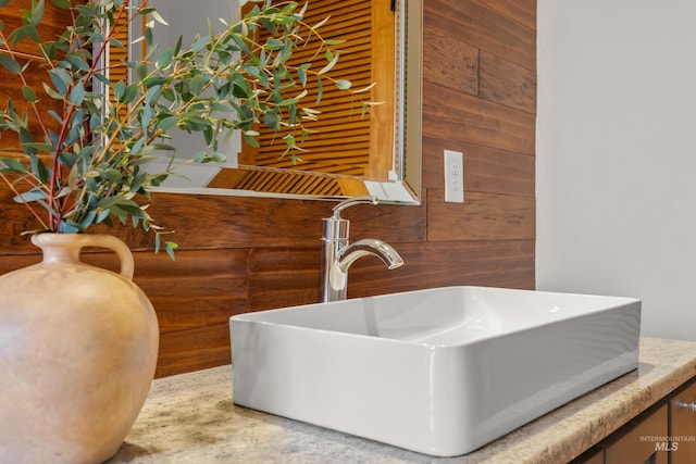 bathroom featuring wooden walls and a sink
