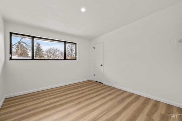 spare room featuring a wealth of natural light, light wood-style floors, and baseboards