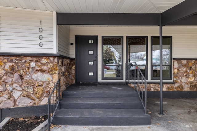 entrance to property featuring a porch and stone siding