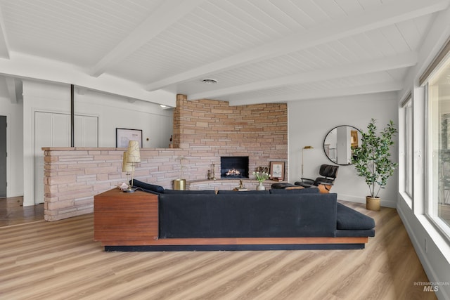 living area featuring baseboards, beam ceiling, wood finished floors, and a fireplace