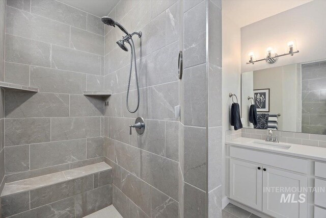 bathroom featuring tiled shower and vanity