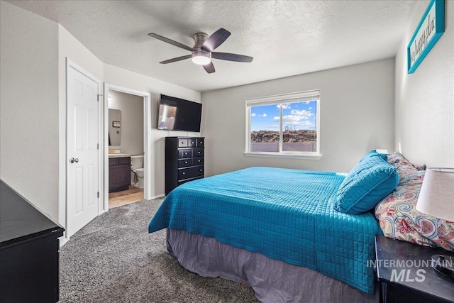 bedroom featuring ceiling fan, ensuite bath, carpet floors, and a textured ceiling