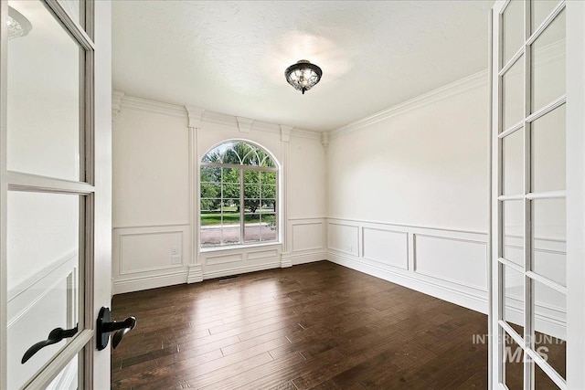 empty room with french doors, a textured ceiling, dark hardwood / wood-style floors, and ornamental molding