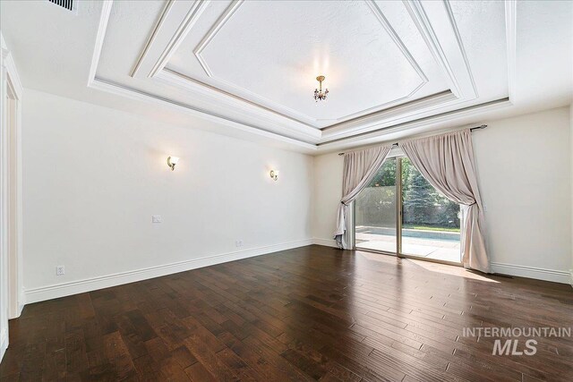 spare room featuring a textured ceiling, dark wood-type flooring, and a tray ceiling