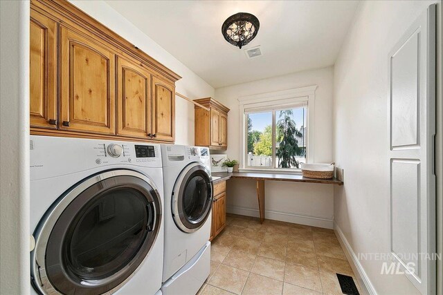 clothes washing area with washer and dryer, cabinets, and light tile patterned flooring