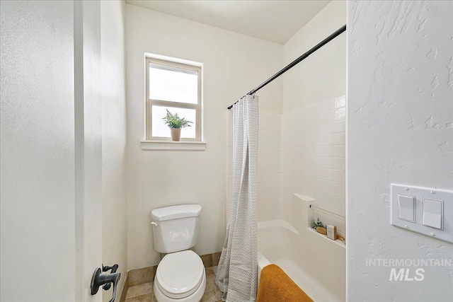 bathroom with tile patterned flooring, shower / bath combo, and toilet