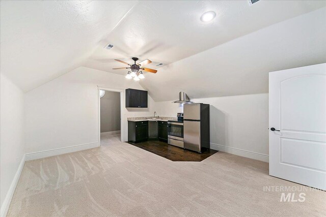 additional living space with dark colored carpet, ceiling fan, sink, and vaulted ceiling