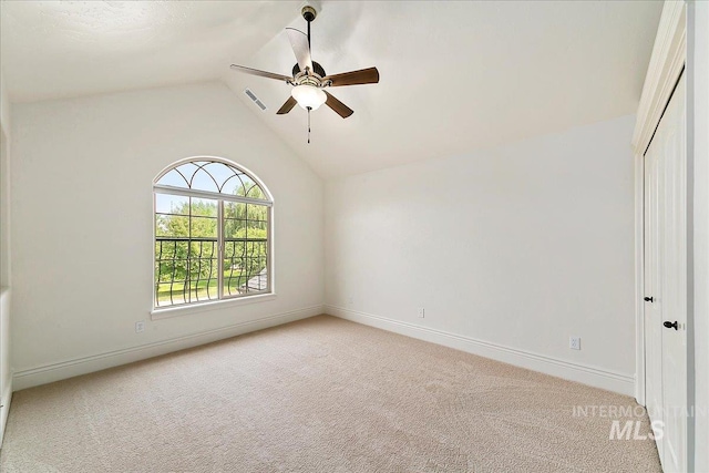 carpeted spare room featuring ceiling fan and vaulted ceiling