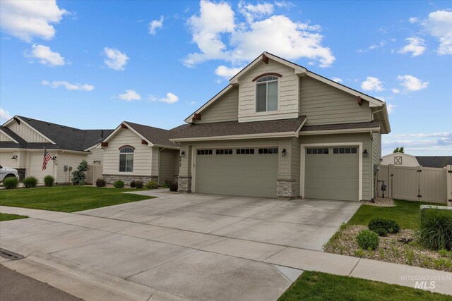 6413 E E Path, Nampa, ID 83687 - view of front of house with a gate, concrete driveway, an attached garage, a shingled roof, and stone siding