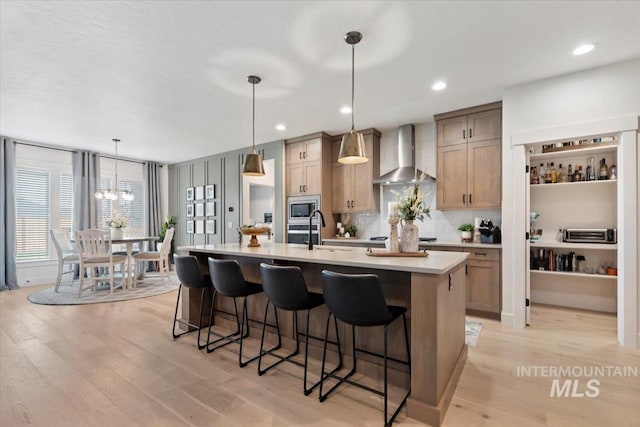 203 S Fusion Ave, Kuna, ID 83634 - kitchen with wall chimney range hood, a sink, stainless steel microwave, a center island with sink, and a kitchen bar