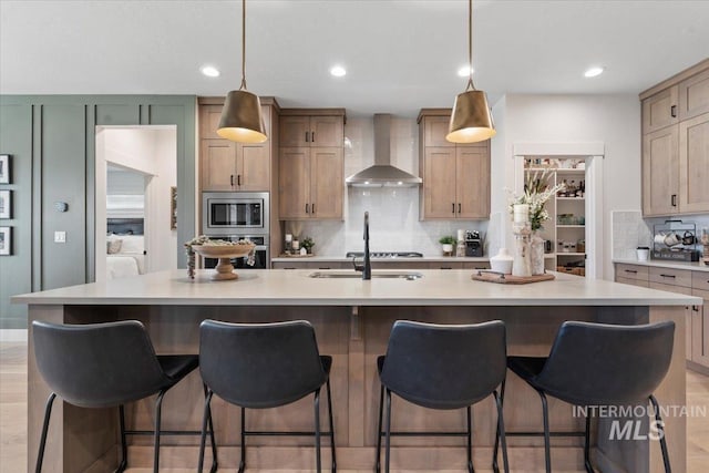 203 S Fusion Ave, Kuna, ID 83634 - kitchen featuring wall chimney exhaust hood, appliances with stainless steel finishes, backsplash, light countertops, and decorative light fixtures