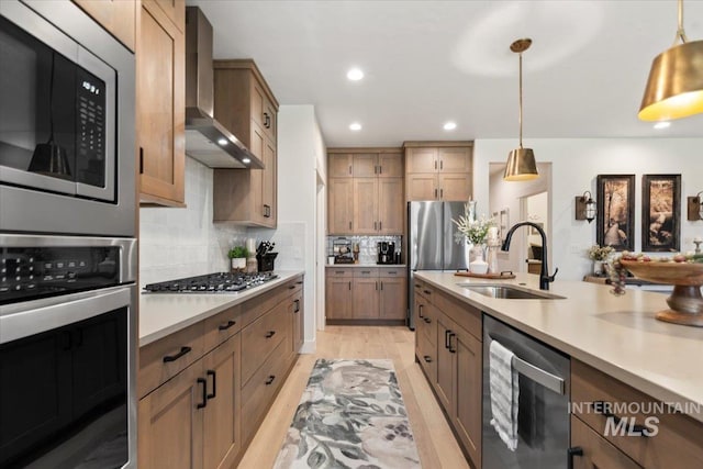 203 S Fusion Ave, Kuna, ID 83634 - kitchen featuring stainless steel appliances, a sink, wall chimney range hood, light countertops, and decorative light fixtures