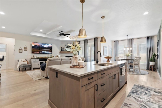 203 S Fusion Ave, Kuna, ID 83634 - kitchen featuring a sink, dishwasher, light wood-style flooring, light countertops, and an island with sink