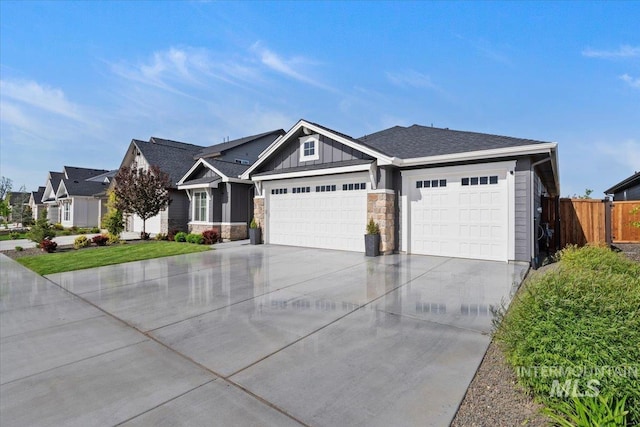 203 S Fusion Ave, Kuna, ID 83634 - view of front of home featuring an attached garage, driveway, fence, board and batten siding, and stone siding