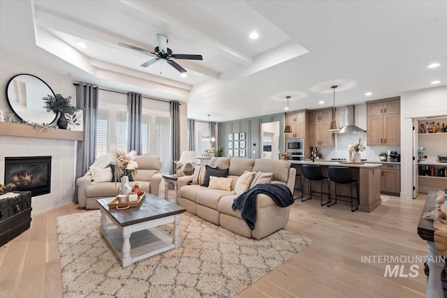 203 S Fusion Ave, Kuna, ID 83634 - living room with recessed lighting, ceiling fan, a tile fireplace, light wood-style floors, and a raised ceiling