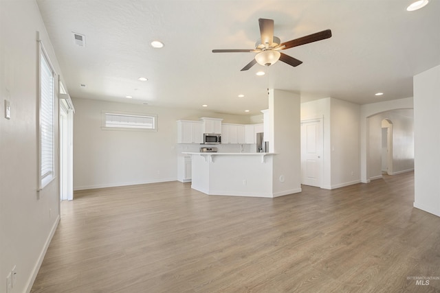 10663 W Catmint, Star, ID 83669 - unfurnished living room with arched walkways, a ceiling fan, baseboards, light wood-type flooring, and recessed lighting