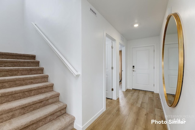 hall featuring light wood-style floors, stairway, baseboards, and recessed lighting