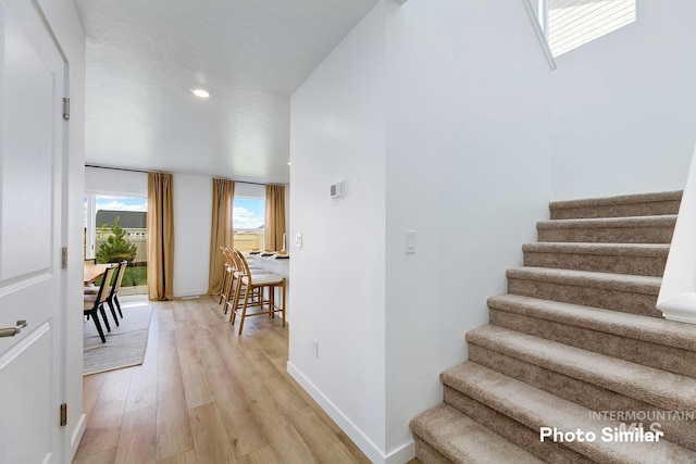 staircase featuring wood finished floors, baseboards, and recessed lighting