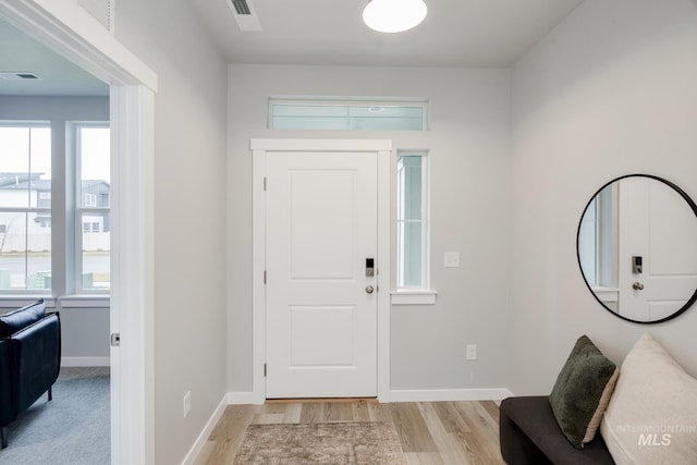 foyer entrance with baseboards, visible vents, and light wood finished floors