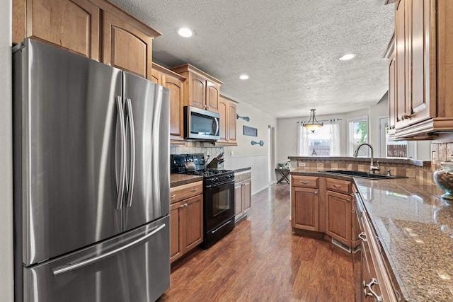 kitchen with appliances with stainless steel finishes, a sink, backsplash, a peninsula, and a textured ceiling