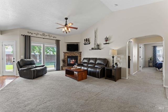 living room featuring a ceiling fan, arched walkways, carpet floors, and vaulted ceiling