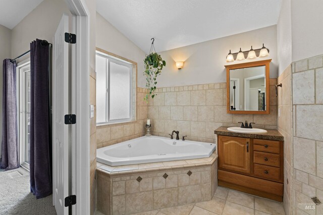 bathroom with tile walls, a bath, vanity, tile patterned flooring, and lofted ceiling