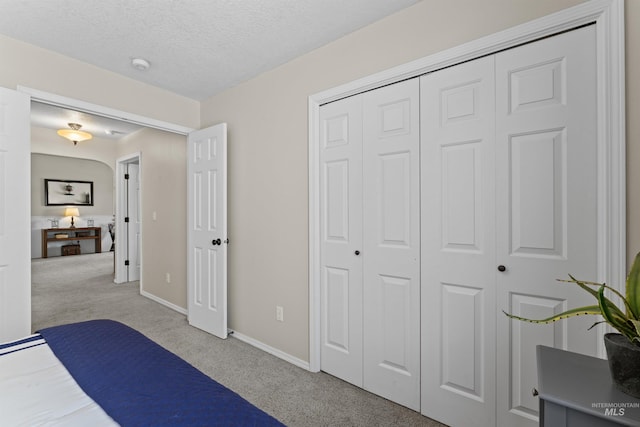 bedroom featuring carpet, baseboards, a closet, and a textured ceiling