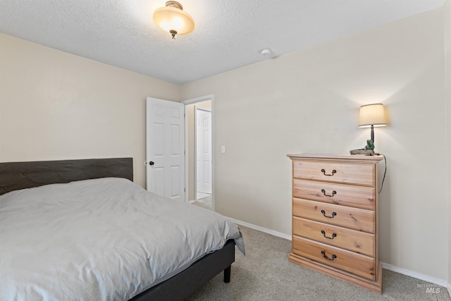 bedroom featuring baseboards, light carpet, and a textured ceiling