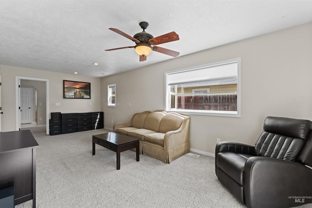 living area with ceiling fan, baseboards, carpet floors, and a textured ceiling