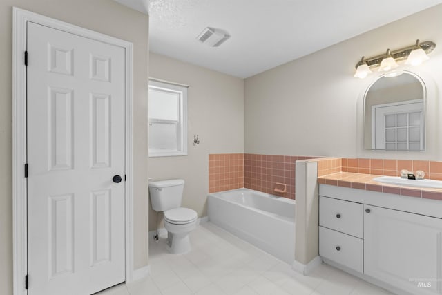 full bath featuring toilet, a bath, vanity, tile patterned floors, and baseboards