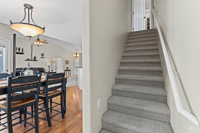 stairs featuring wood finished floors, a chandelier, arched walkways, and lofted ceiling