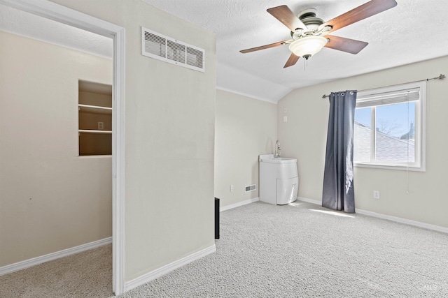 unfurnished room featuring a ceiling fan, carpet floors, baseboards, lofted ceiling, and a textured ceiling