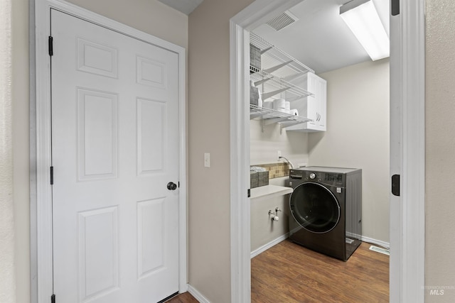 laundry area featuring washer / clothes dryer, cabinet space, wood finished floors, and baseboards