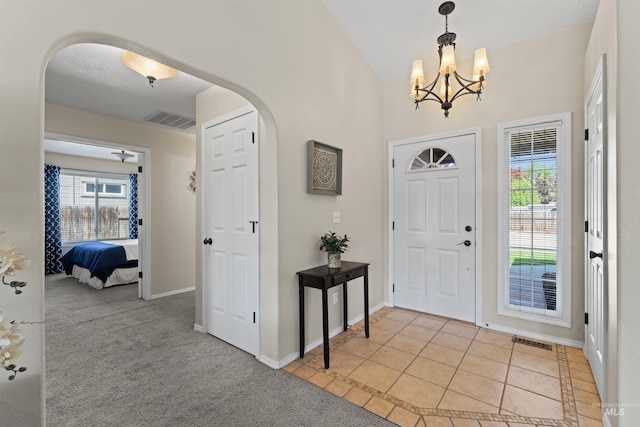 entrance foyer with arched walkways, healthy amount of natural light, a chandelier, and baseboards
