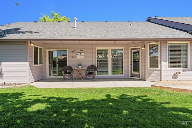 back of property with a yard, a patio, and a shingled roof