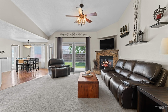 living room featuring ceiling fan, vaulted ceiling, a fireplace, plenty of natural light, and carpet