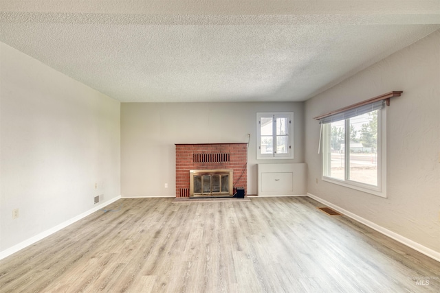 unfurnished living room with a fireplace, light hardwood / wood-style flooring, and a textured ceiling