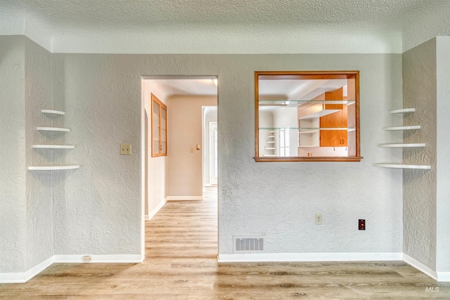 spare room featuring wood-type flooring and a textured ceiling