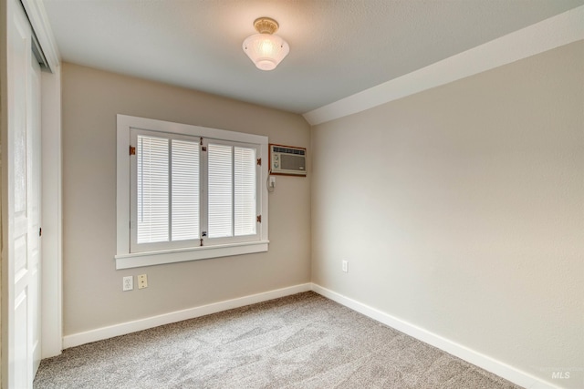 carpeted empty room featuring an AC wall unit and vaulted ceiling