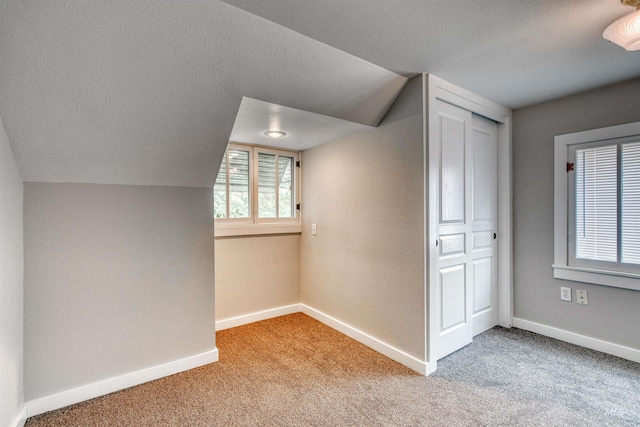 bonus room with carpet flooring, a textured ceiling, and lofted ceiling