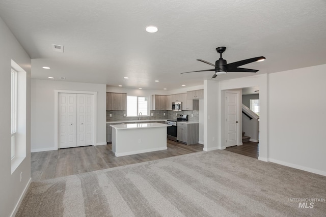 kitchen with modern cabinets, a center island, stainless steel appliances, light countertops, and a sink