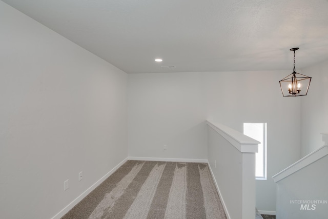 carpeted spare room featuring a chandelier, stairs, visible vents, and baseboards