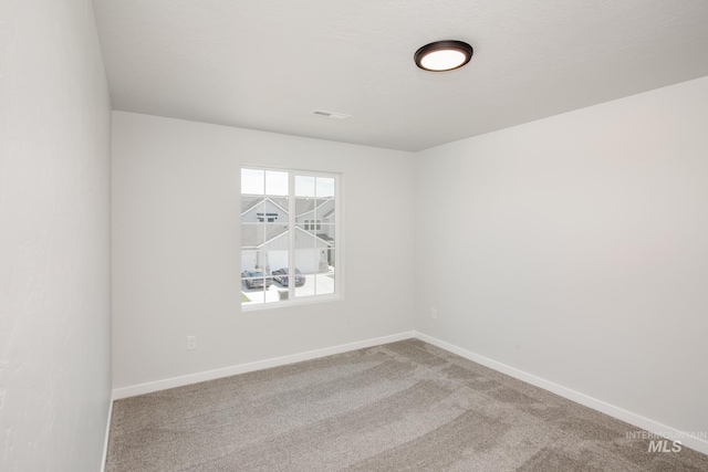 empty room with carpet flooring, visible vents, and baseboards