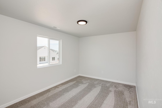 empty room featuring carpet and baseboards