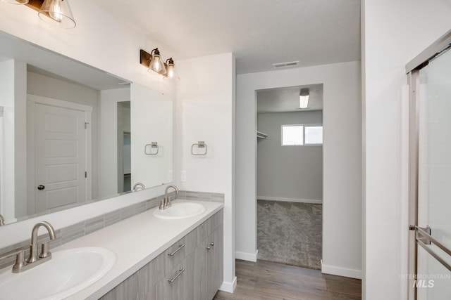 bathroom featuring double vanity, baseboards, visible vents, and a sink