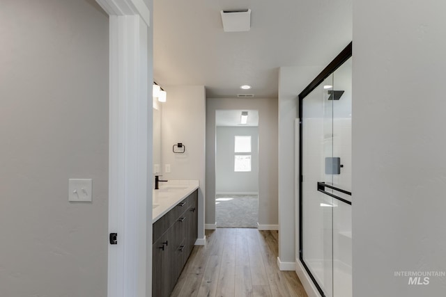 bathroom featuring wood finished floors, a shower stall, vanity, and baseboards