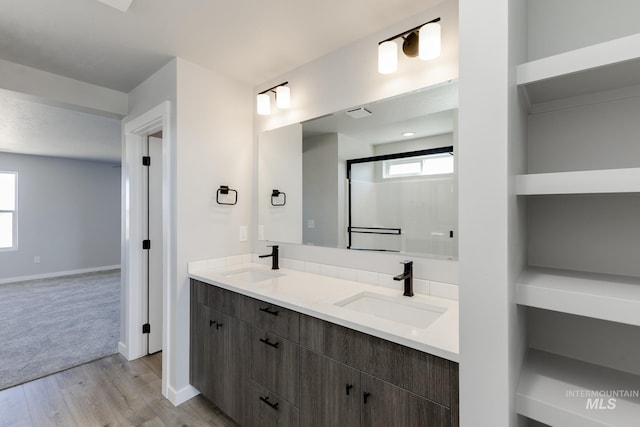 bathroom featuring double vanity, a sink, wood finished floors, and baseboards