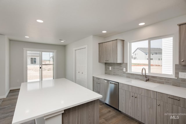 kitchen with a center island, light countertops, dark wood-type flooring, a sink, and dishwasher