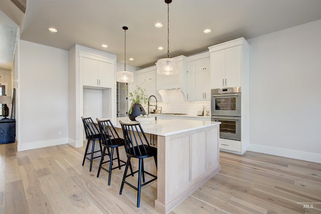 4219 W Thornapple Dr, Meridian, ID 83646 - kitchen featuring double oven, light wood-type flooring, a kitchen island with sink, decorative backsplash, and recessed lighting